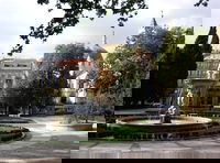 Fountain in foreground in Parque Del Retiro, Calle de Alcalá in the middle ground, and an unnamed church in the background. Near the Retiro metro stop.