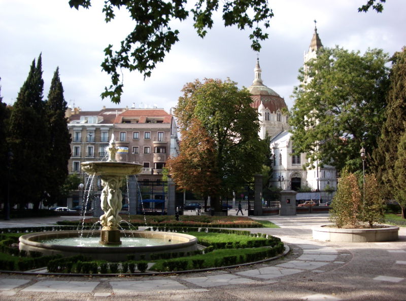 Fountain in foreground in Parque Del Retiro, Calle de Alcalá in the middle ground, and an unnamed church in the background. Near the Retiro metro stop.