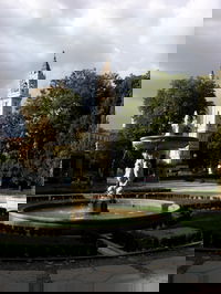 Fountain in foreground in Parque Del Retiro, Calle de Alcalá in the middle ground, and an unnamed church in the background. Near the Retiro metro stop.